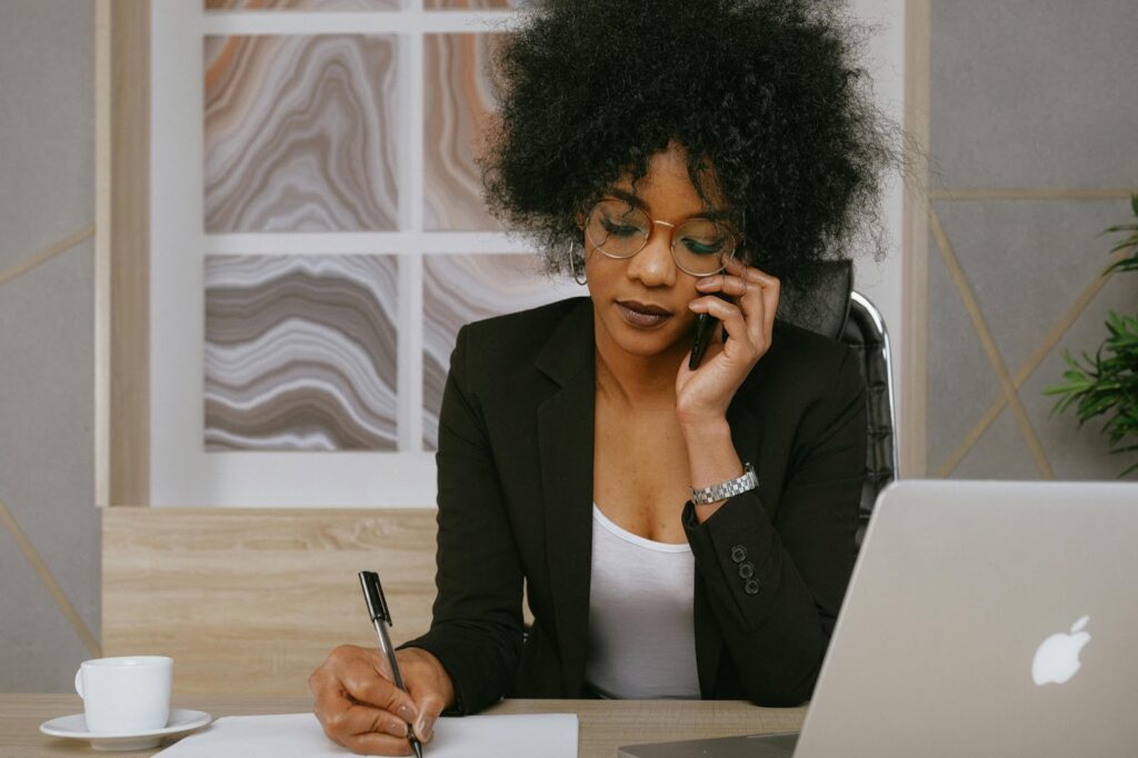 woman working at desk in front of computer and on phone