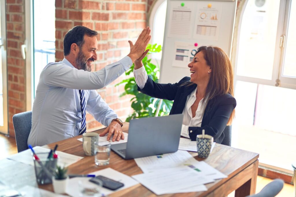 people highfiving at desk after winning one of their sales contest ideas