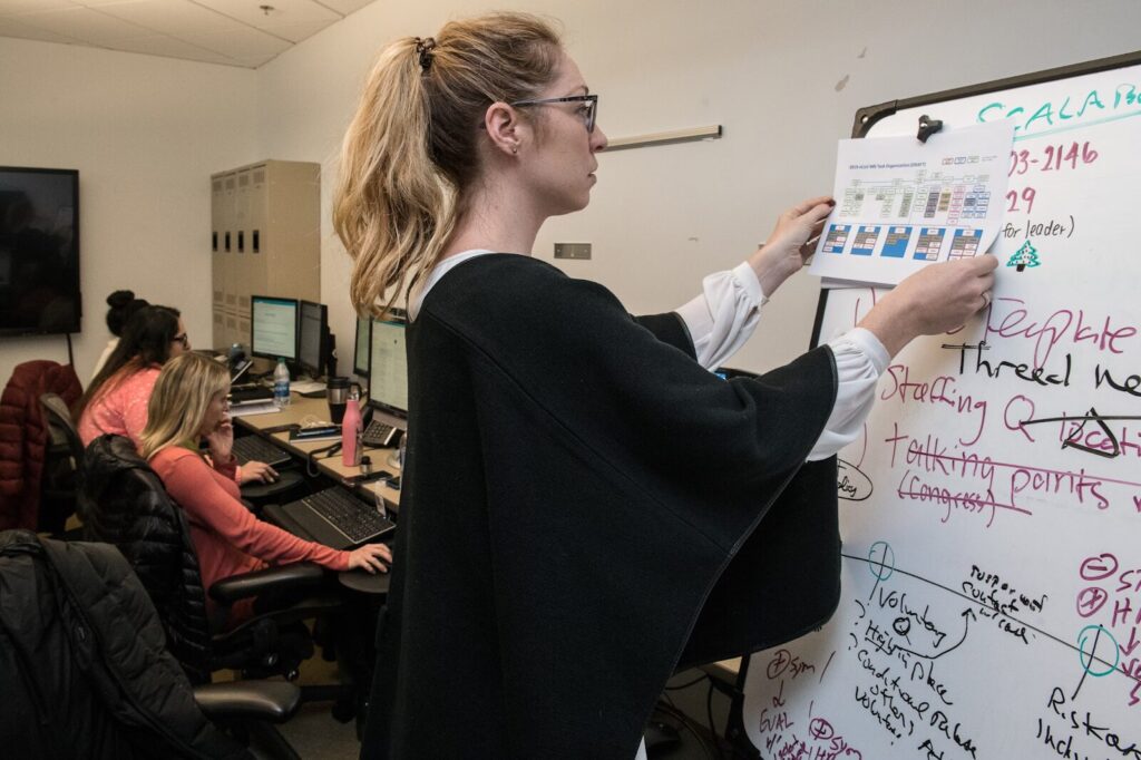 Woman at work adding spreadsheet to markerboard