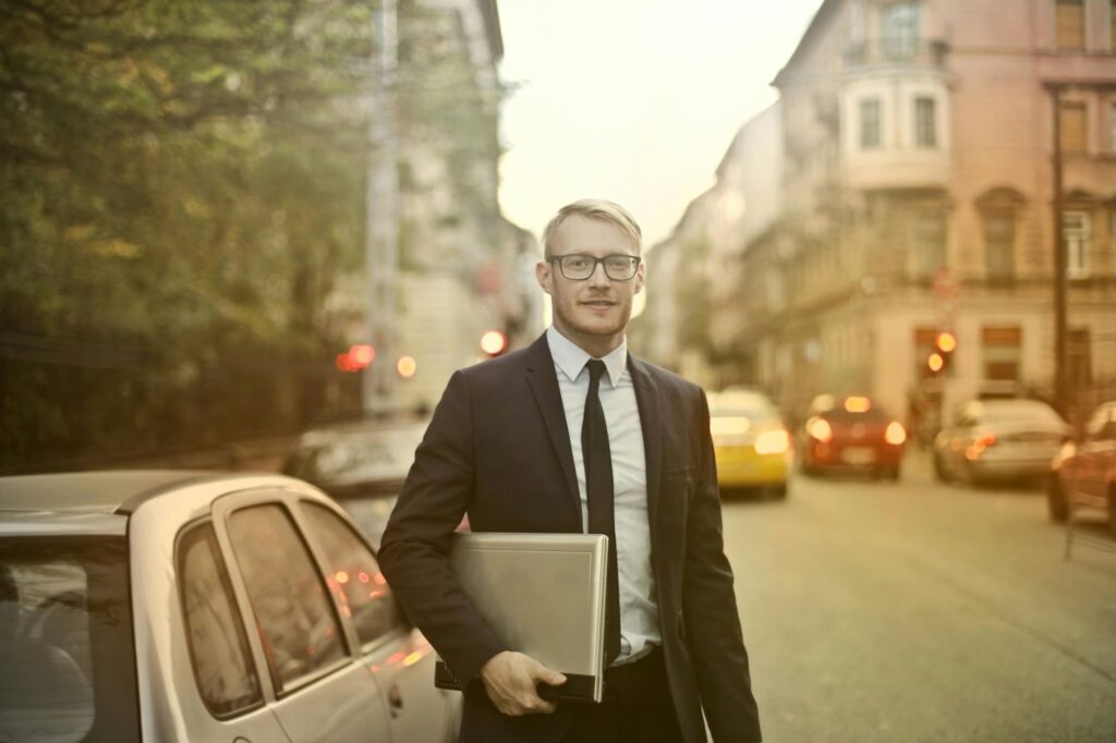 man standing in traffic with work computer